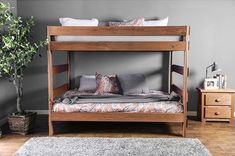 a wooden bunk bed sitting on top of a hard wood floor next to a potted plant