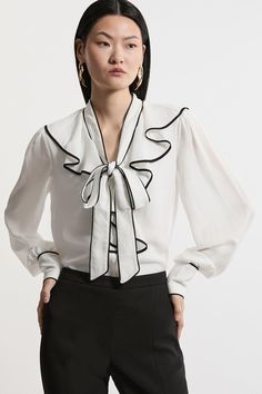 Elevate Your Top Selection With Our Blouse, Which Boasts A Relaxed Fit, And A Statement Bow And Ruffle Design, Ideal For Enriching Your Occasion Wear Selection. This Piece Pairs Well With Anything, From A Fitted Midi Skirt, To Tailored Trousers, To Jeans For An Elevated Look That Will Take You Seamlessly From Day To Night. Georgette Bow Front Woven Blouse High Quality Georgette Fabric Statement Bow Accent Feminine Ruffle Detailing Comfortable, Relaxed Fit Formal High Neckline Luxury Chic Blouse With Ruffle Sleeves, Luxury Ruffle Sleeve Elegant Blouse, Luxury Long Sleeve Blouse With Bow, Luxury White Ruffle Sleeve Blouse, Luxury Button-up Blouse With Ruffles, Bride Jumpsuit, Petite Wedding Guest Dresses, Fitted Midi Skirt, Outfits Petite