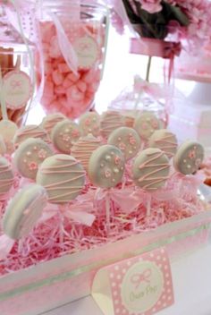 pink and white candies in a box on a table with other candy items behind it