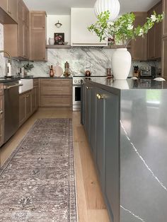 a kitchen with wooden cabinets and stainless steel appliances, including a large rug in the middle