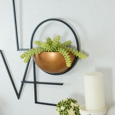 a candle and some flowers on a shelf next to a metal wall decoration with the word love