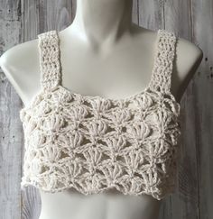 a mannequin wearing a white crochet top on a wooden surface with wood planks