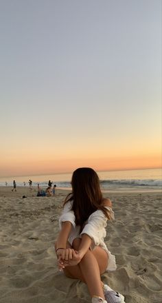 a woman sitting on top of a sandy beach