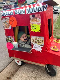 a child in a red cart with tacos on it's head and name written on the side