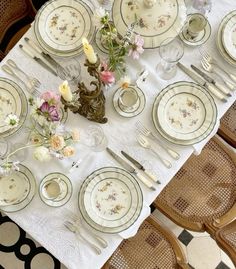 the table is set with plates, silverware and flowers on it for a formal dinner