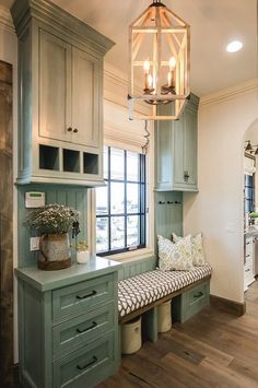 a kitchen with green cabinets and a bench in front of the window that has a cushion on it