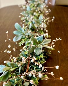 the table is covered with greenery and white flowers on it's long stems