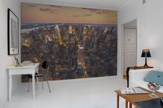 a living room filled with furniture and a large cityscape wall mural on the wall