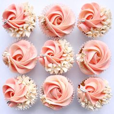 nine cupcakes with pink frosting and white flowers on them are arranged in rows