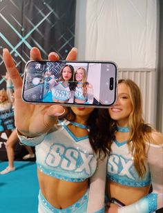 two cheerleaders taking a selfie with their cell phone in front of them