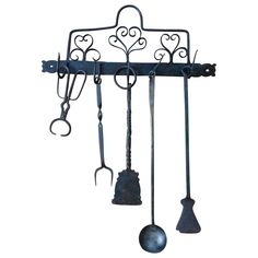 an iron rack with several kitchen utensils hanging from it's sides and two spoons attached to the hooks