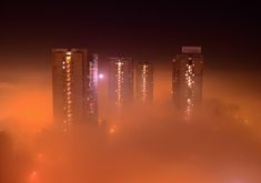 fog covers the city at night with tall buildings in the distance