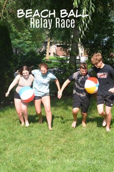 four children are playing with beach balls in the grass