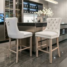 two white bar stools sitting in front of a counter