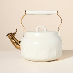 a white tea pot with a gold handle