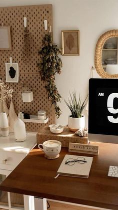 a desktop computer sitting on top of a wooden desk next to a potted plant