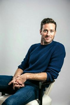 a man sitting on top of a white chair with his legs crossed in front of him