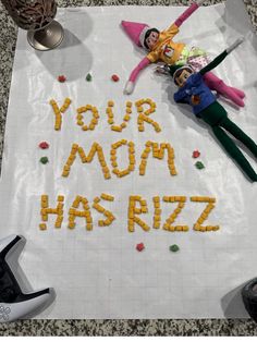 the word your mom has rizzi spelled out on a sheet of paper next to two dolls