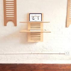 a white brick wall with some wooden shelves on it and a computer monitor sitting on top of the shelf