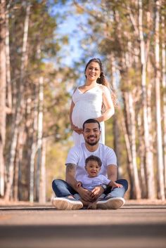 a man and woman are sitting on the ground with a baby in front of them