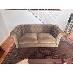 a couch sitting on top of a rug in a living room next to a stair case