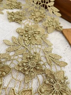 an embroidered lace with flowers and leaves is shown on a white tablecloth next to a wooden cutting board