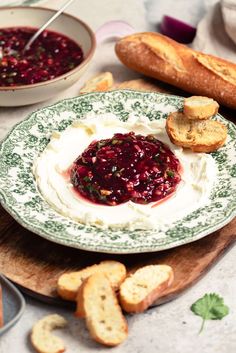 a bowl of cream cheese and cranberry sauce on a plate with bread slices