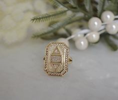 a gold ring sitting on top of a white table next to flowers and greenery