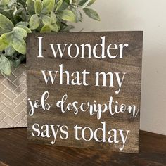 a wooden sign that says i wonder what my job description says today next to a potted plant