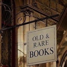 an old and rare book store sign hanging from the side of a building