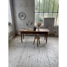 a table with two stools in front of it and a vase on the floor