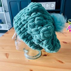 a blue hat on top of a head on a wooden table in front of a tv