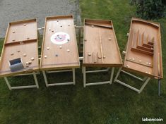 three wooden tables sitting on top of a grass covered field next to each other with pegs in them