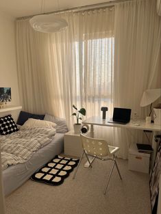 a bedroom with a bed, desk and chair in front of a window overlooking the city