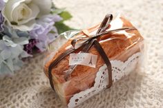 a piece of bread wrapped in brown ribbon next to purple and white flowers on a table