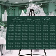 a green and white wedding seating chart on a easel in front of a banquet table