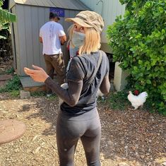 a woman wearing a face mask and leggings standing in front of a house