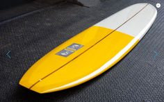 a yellow and white surfboard laying on the ground