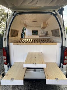 the back end of a van with wooden tables in it