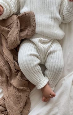 a baby laying on top of a white blanket