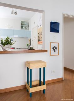 a small wooden stool sitting in front of a kitchen counter next to a wall mounted mirror