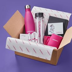 an open box with various items in it on a purple background, including a water bottle