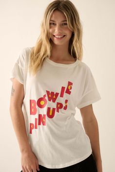 David Bowie Pinups Garment-Wash Graphic Tee - ShopPromesa Relaxed Fit Pop Culture T-shirt With Text Print, Pop Culture Cotton Top With Graphic Print, Pop Culture Short Sleeve Slogan Top, Pop Culture Short Sleeve Top With Slogan, Pop Culture Graphic Print Tops In Relaxed Fit, Relaxed Fit Graphic Print Tops Pop Culture, Relaxed Fit Graphic Print Tops For Pop Culture, Band Merch Cotton Top With Front Print, Cotton Band Merch Top With Front Print