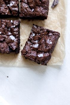 chocolate brownies with sea salt on top are cut into squares and placed on parchment paper