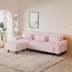 a pink couch sitting on top of a wooden floor next to a lamp and rug