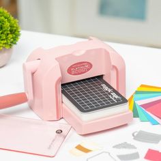 a pink machine sitting on top of a table next to some cut outs and paper