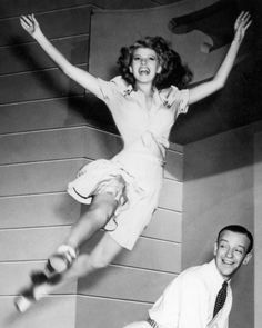 an old black and white photo of two people jumping in the air