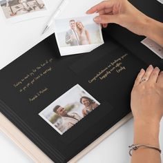 a woman is holding an open book with photos on it and writing in gold ink