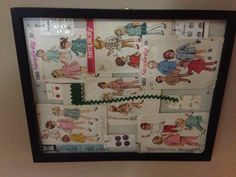 a wall hanging on the side of a wall covered in paper dolls and children's clothes