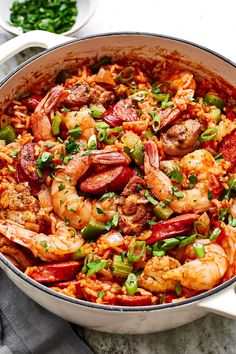 shrimp and sausage paella in a pot with a wooden spoon on the side, ready to be eaten